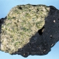 Esempio di xenolite proveniente dalla parte alta del  mantello: un nodulo di peridotite (verde chiaro) avvolto da una crosta nera di basalto.